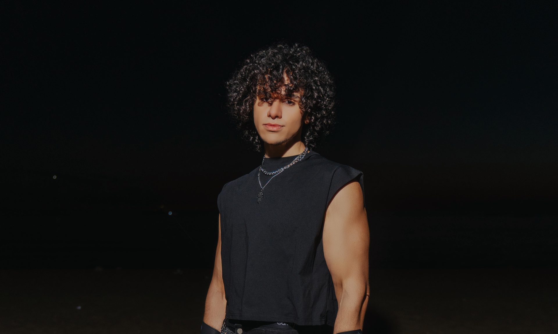 Bahjat standing in the desert at night, dressed in black.