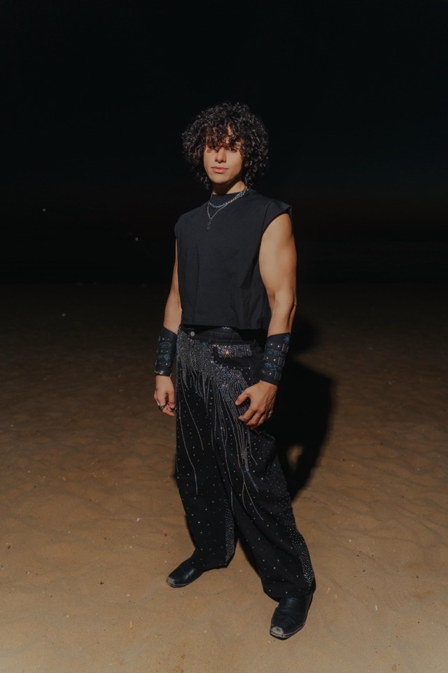 Bahjat standing in the desert at night, dressed in black.